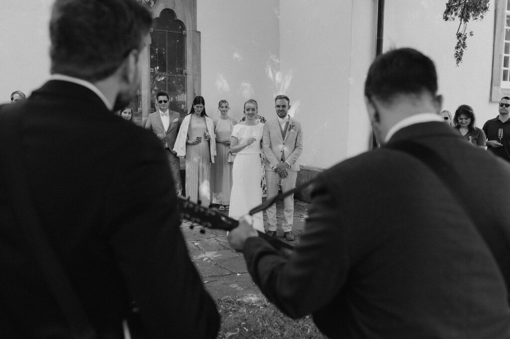 Live-Musik während des Empfangs vor der Kirche – Blick auf das Brautpaar.