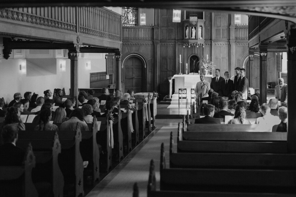 Gäste und Bräutigam warten in der Kirche auf den Einzug der Braut.