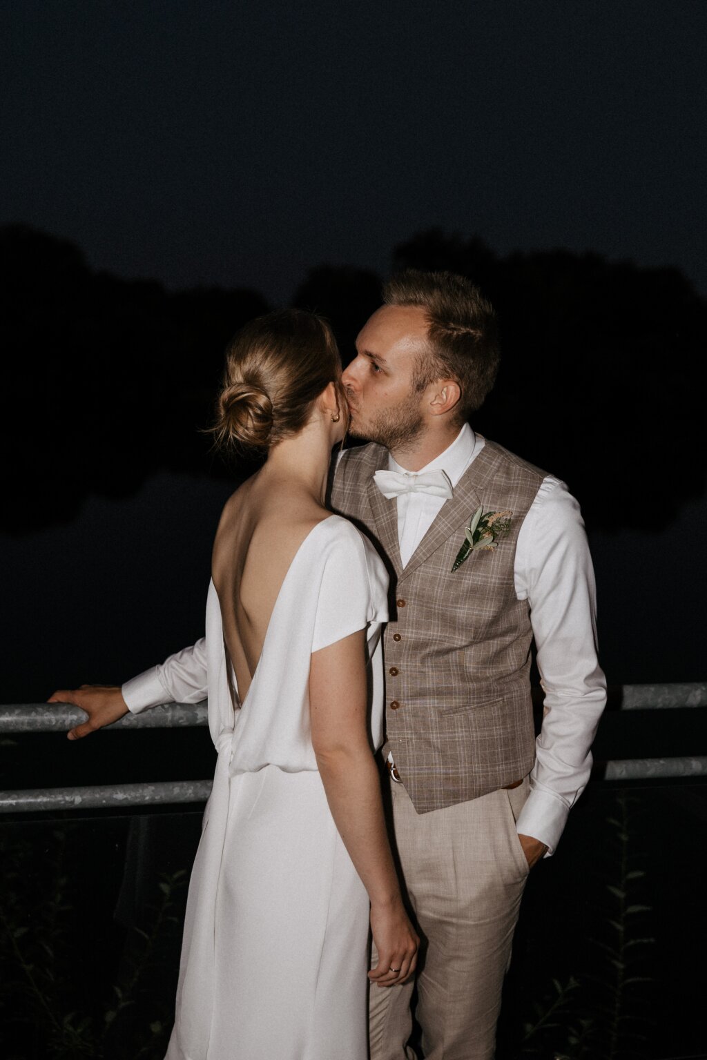 Hochzeitspaar küsst sich zärtlich bei Nacht am Wasser – romantisches Abschlussbild.