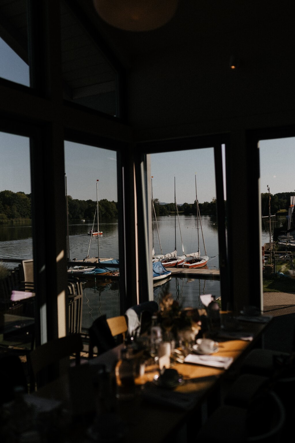 Blick durch das Fenster auf Boote am See neben dem Restaurant.
