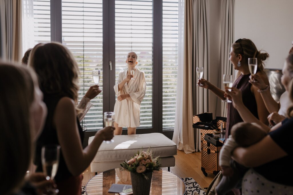 Braut beim Anstoßen mit Freundinnen während des Getting Ready.