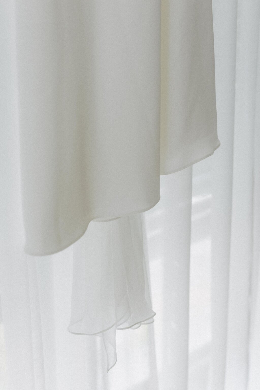 Detailaufnahme des schwebenden Stoffs eines Brautkleids vor Vorhang.