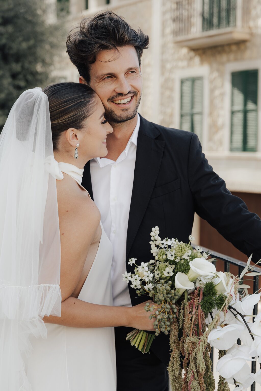 Frisch verheiratetes Paar in liebevoller Umarmung vor eleganter Hochzeitslocation.