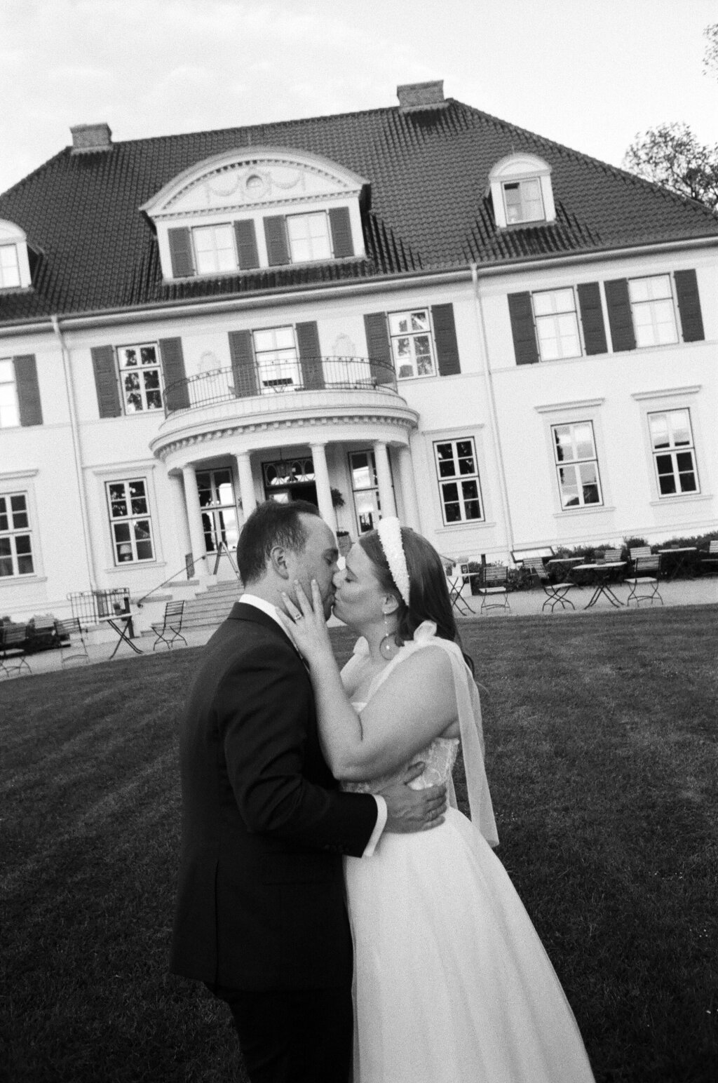 Hochzeitspaar in Schwarz-Weiß vor einer historischen Villa – ein Moment voller zeitloser Romantik.