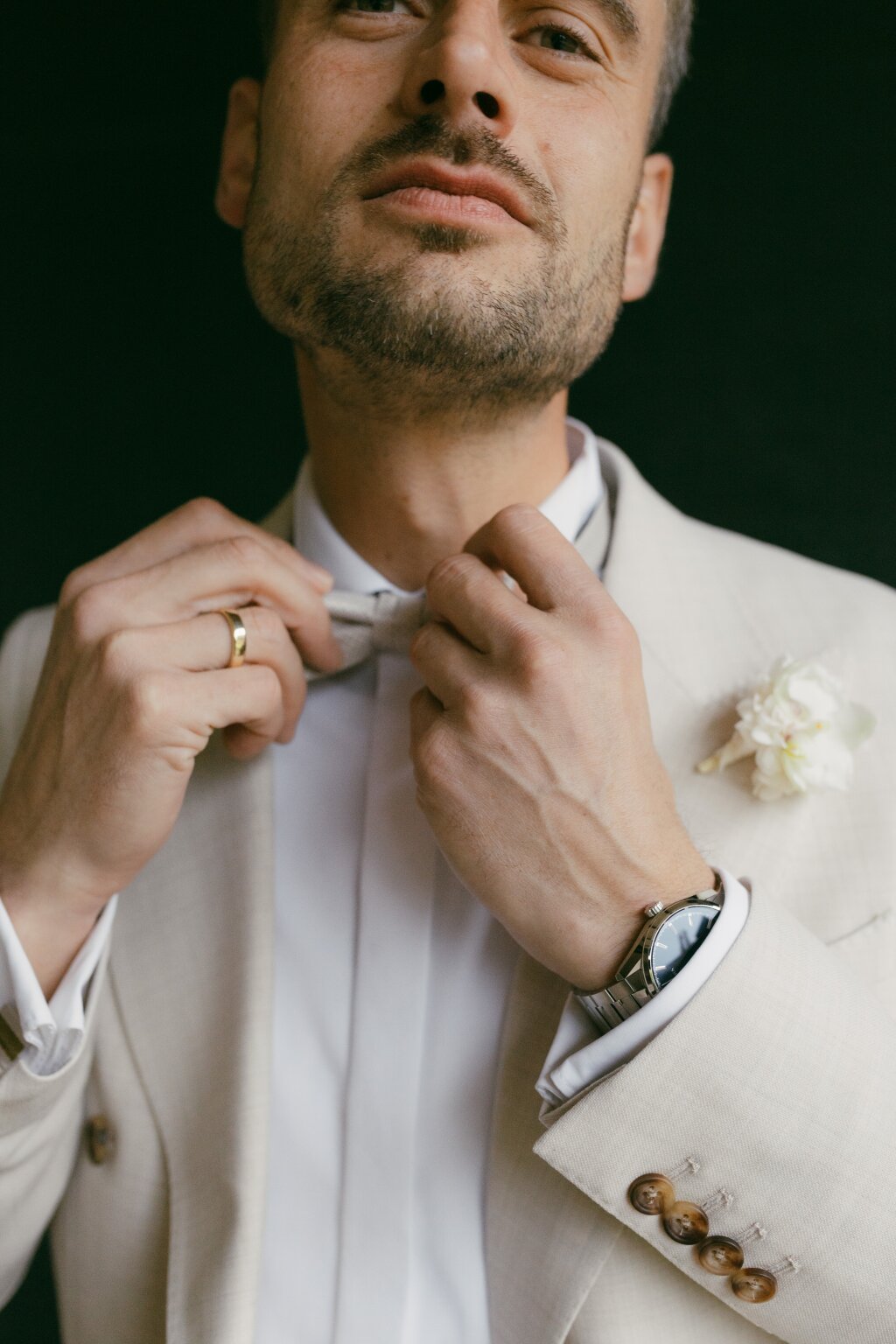 the groom straightens his bow tie.