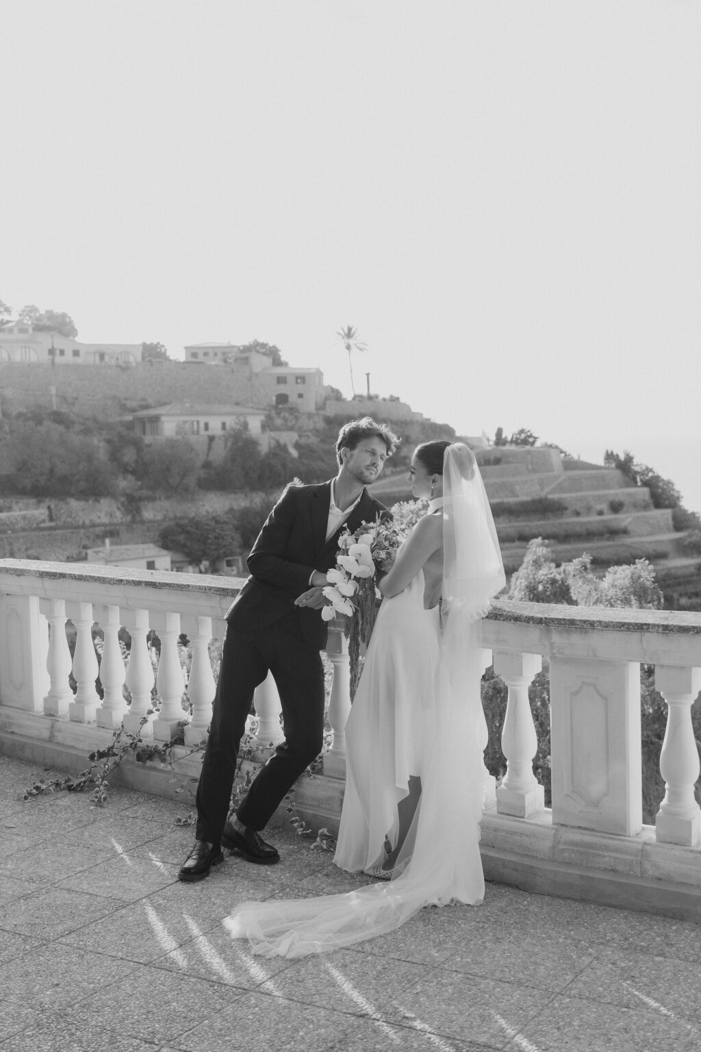 Bride and groom on their wedding day leaning on a railing.